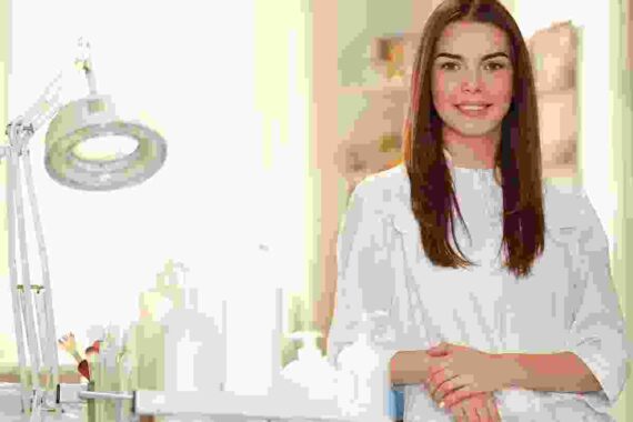 A woman in white shirt standing next to a table.