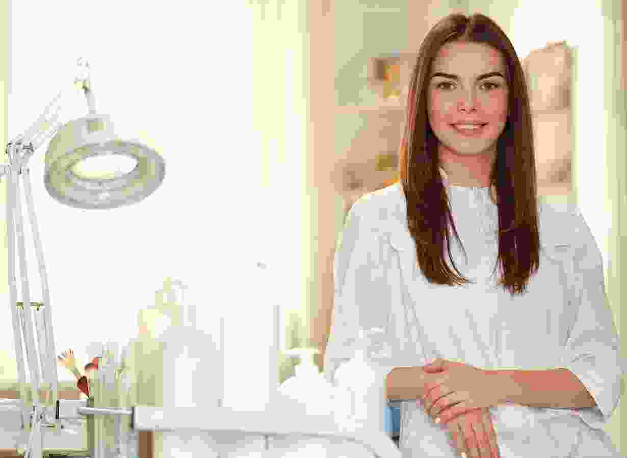 A woman in white shirt standing next to a table.