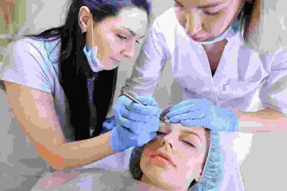 A woman is getting her face waxed by two other women.